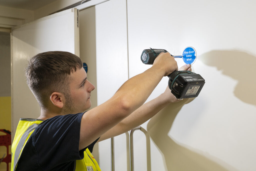 Bell Group Passive fire protection consultant installing a fire safety door in a commercial property.